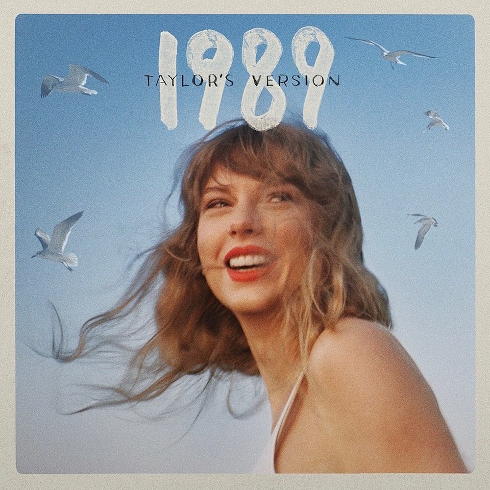 A woman with wavy hair smiles against a blue sky with seagulls. Text above reads 1989 Taylor's Version in large white letters, evoking the style of a Taylor Swift album cover with a vintage photo border.