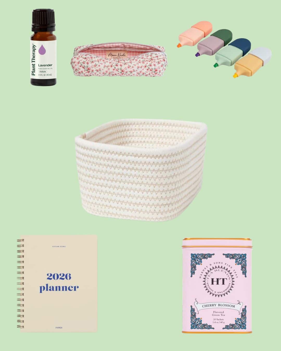 A lavender essential oil bottle, floral pouch, four pastel highlighters, white woven basket, 2026 planner, and a pink cherry blossom tea tin are arranged on a light green background.
