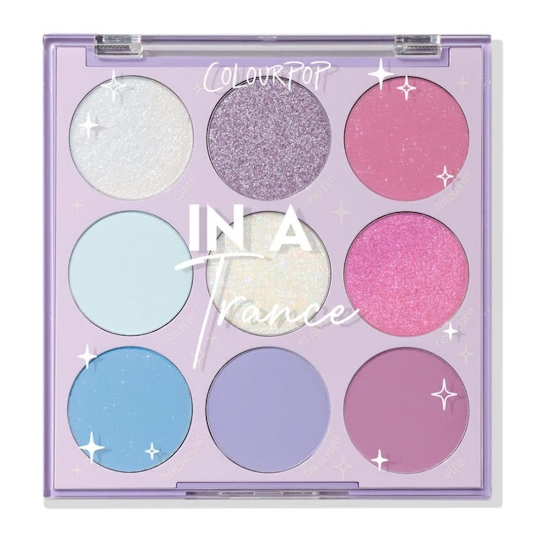 A ColourPop eyeshadow palette called In A Trance with nine pastel and shimmery shades in pink, purple, blue, and white tones—perfect for a full-glam showgirl look—in a square lavender case with sparkly accents on the lid.