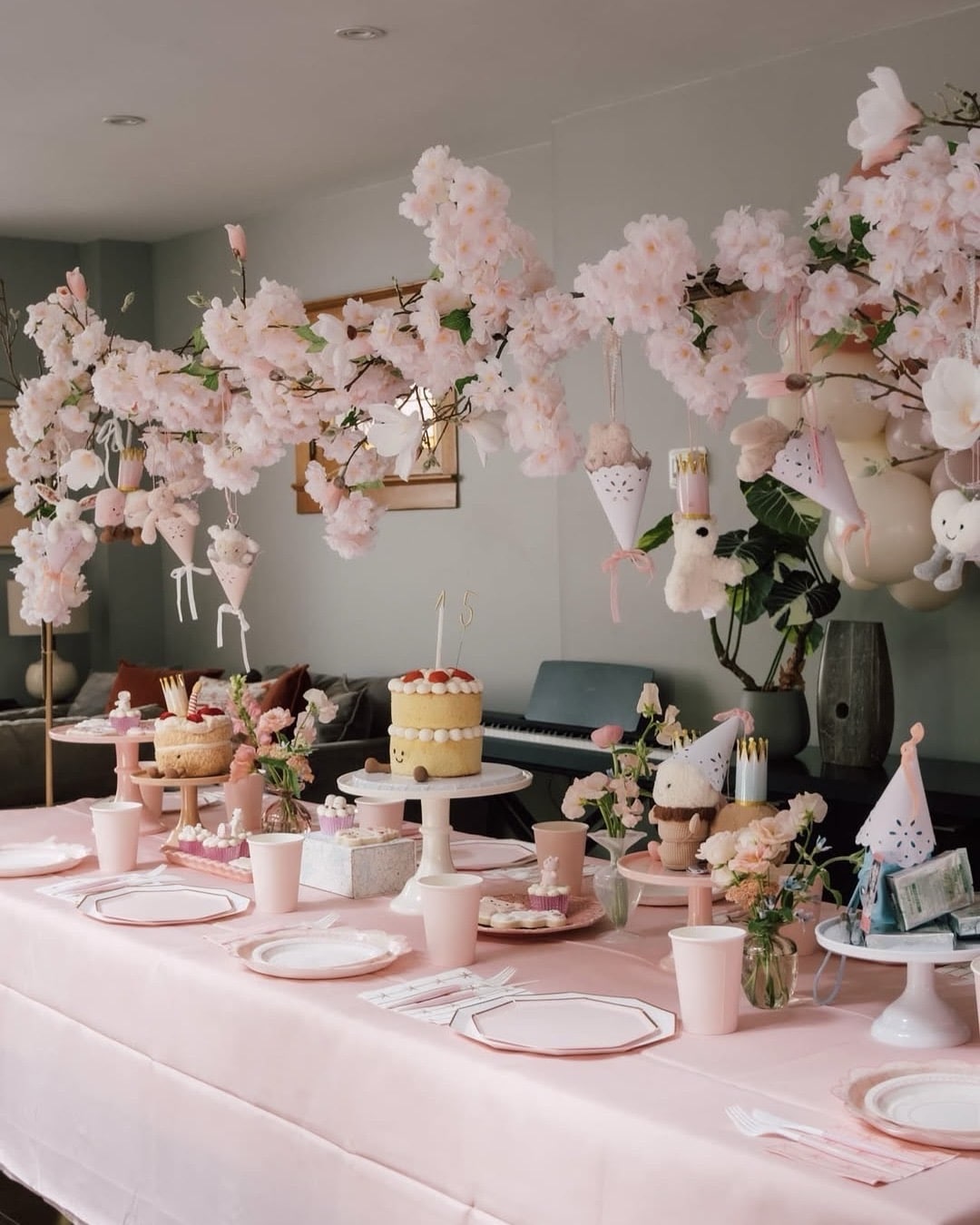 A pastel pink party table is decorated with cherry blossom branches, plush toys, cakes, and sweet treats. Pink cups, plates, and flowers create a festive, elegant atmosphere—perfect to host a Jellycat party or special Jellycat exchange.