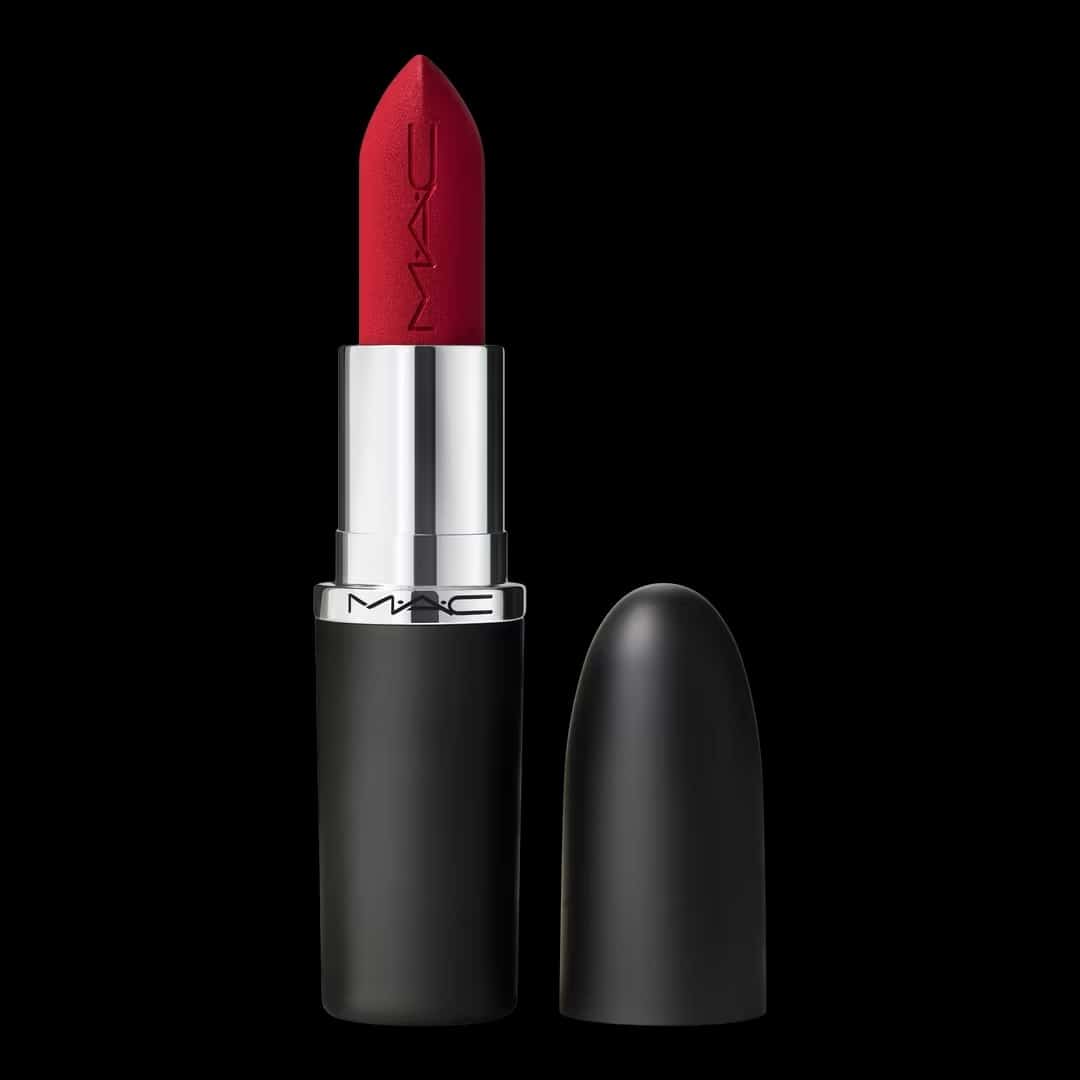 A tube of MAC lipstick in a bold red shade stands upright with its matte black cap beside it, channeling full-glam showgirl energy against a black background. The silver tube features the MAC logo near the base.