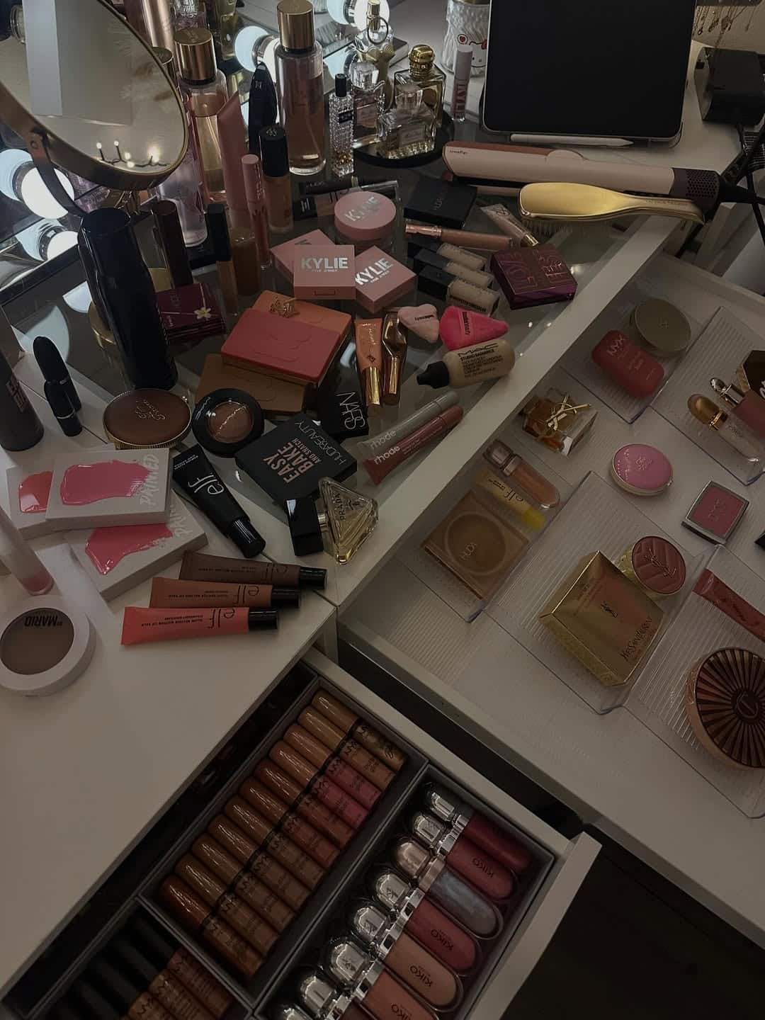 A vanity table with open drawers displays various makeup products, including lipsticks, eyeshadow palettes, and powders—each neatly organized to help you avoid any awkward makeup mishaps.