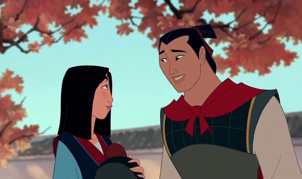 Two animated characters, a woman and a man, stand under autumn trees with red leaves. Reminiscent of classic childhood flicks, the smiling man in armor with a red sash offers love advice to the woman in her blue and red outfit.