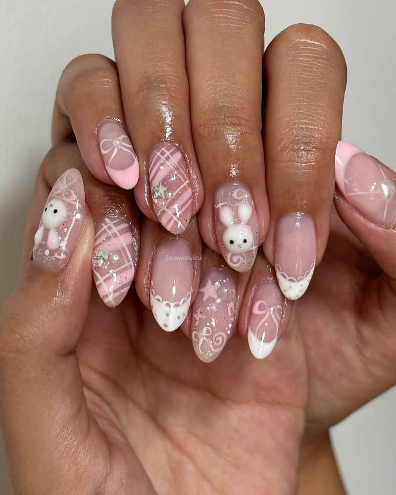 A hand with long, almond-shaped nails featuring pink and white nail art. Designs include plaid patterns, bows, hearts, and cute white bear faces, with some nails decorated with small rhinestones.