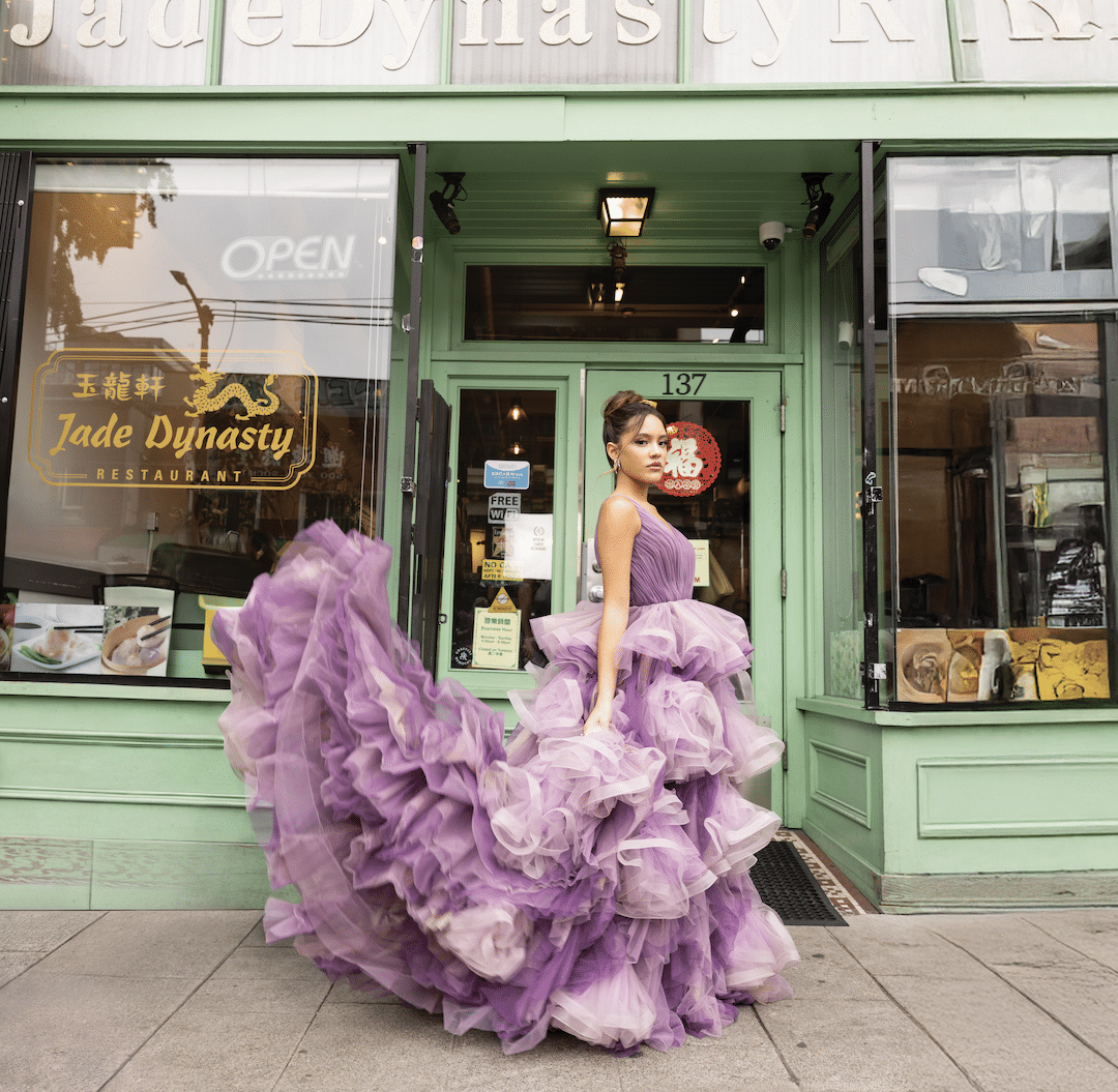 Liamani Segura stuns in a flowing, ruffled purple gown, posing dramatically on the sidewalk in front of a green Jade Dynasty Restaurant storefront—capturing timeless elegance with a 2026 flair.